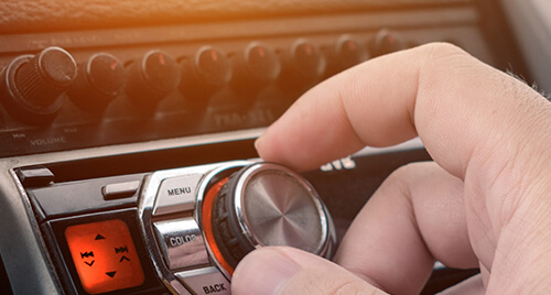 Car Audio: Person's fingers turning the tuning dial on an in-car audio system
